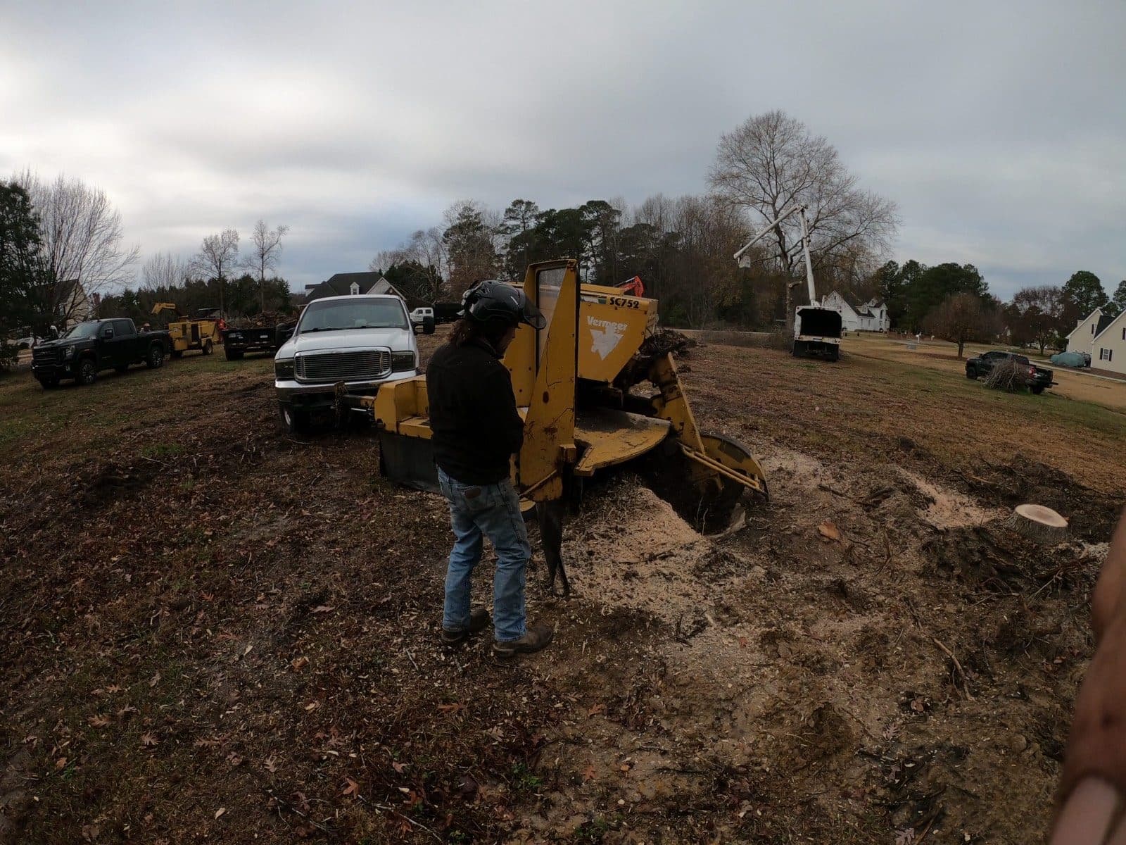 A Tree Works crew member running the stump grinder on a cleared lot