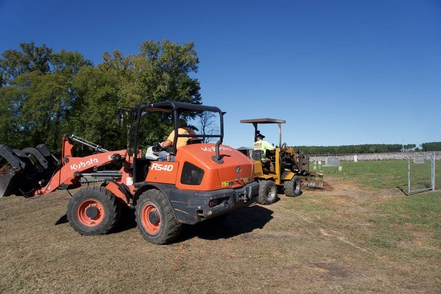 Kubota wheel loader and stump grinder on the job by the field