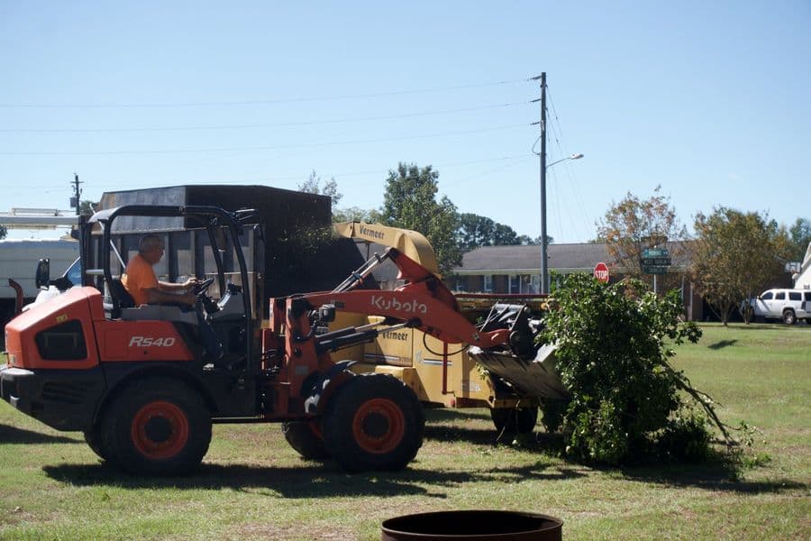 Kubota wheel loader carrying a load of brush across a yard