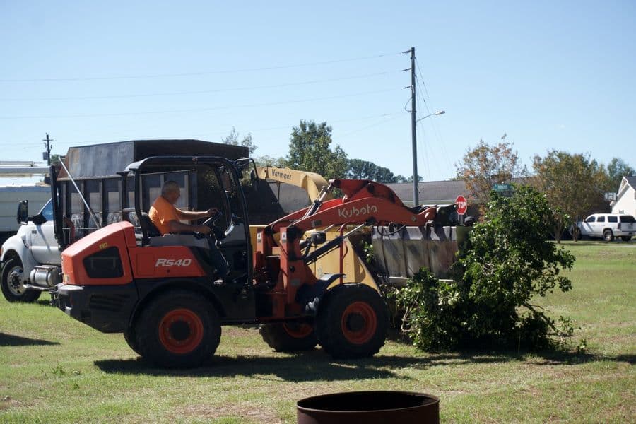 Kubota loader picking up cut brush