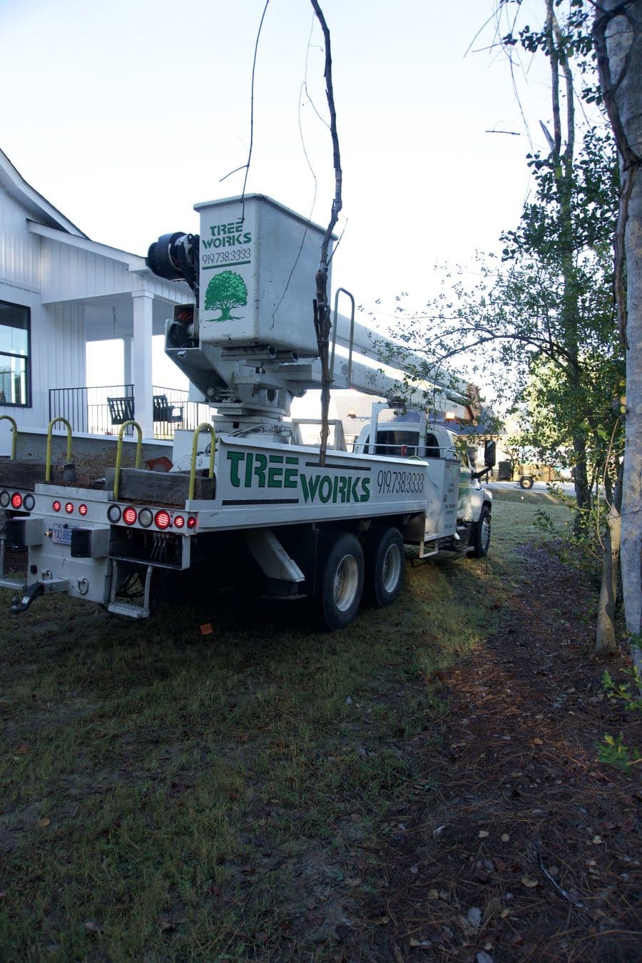 Tree Works bucket truck beside the house with the bucket in the air