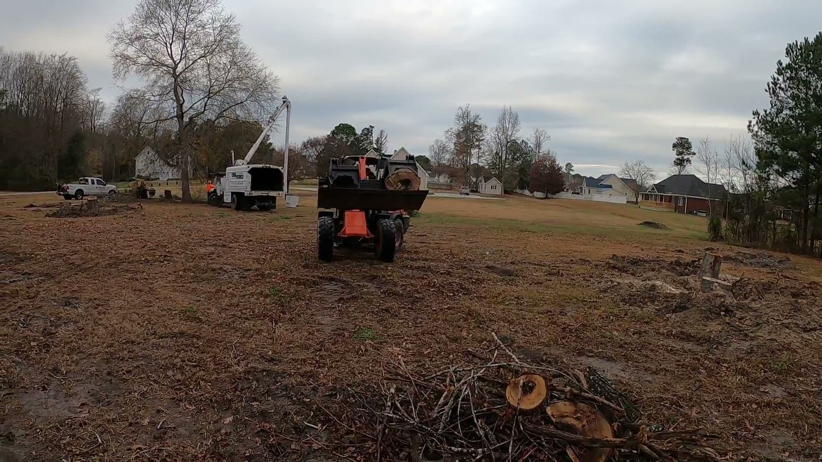 Kubota wheel loader carrying brush across a cleared residential lot