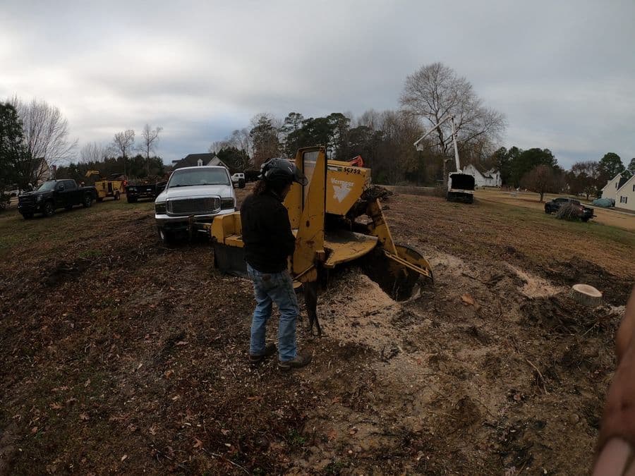 Tree Works crew member running a stump grinder on a cleared residential lot