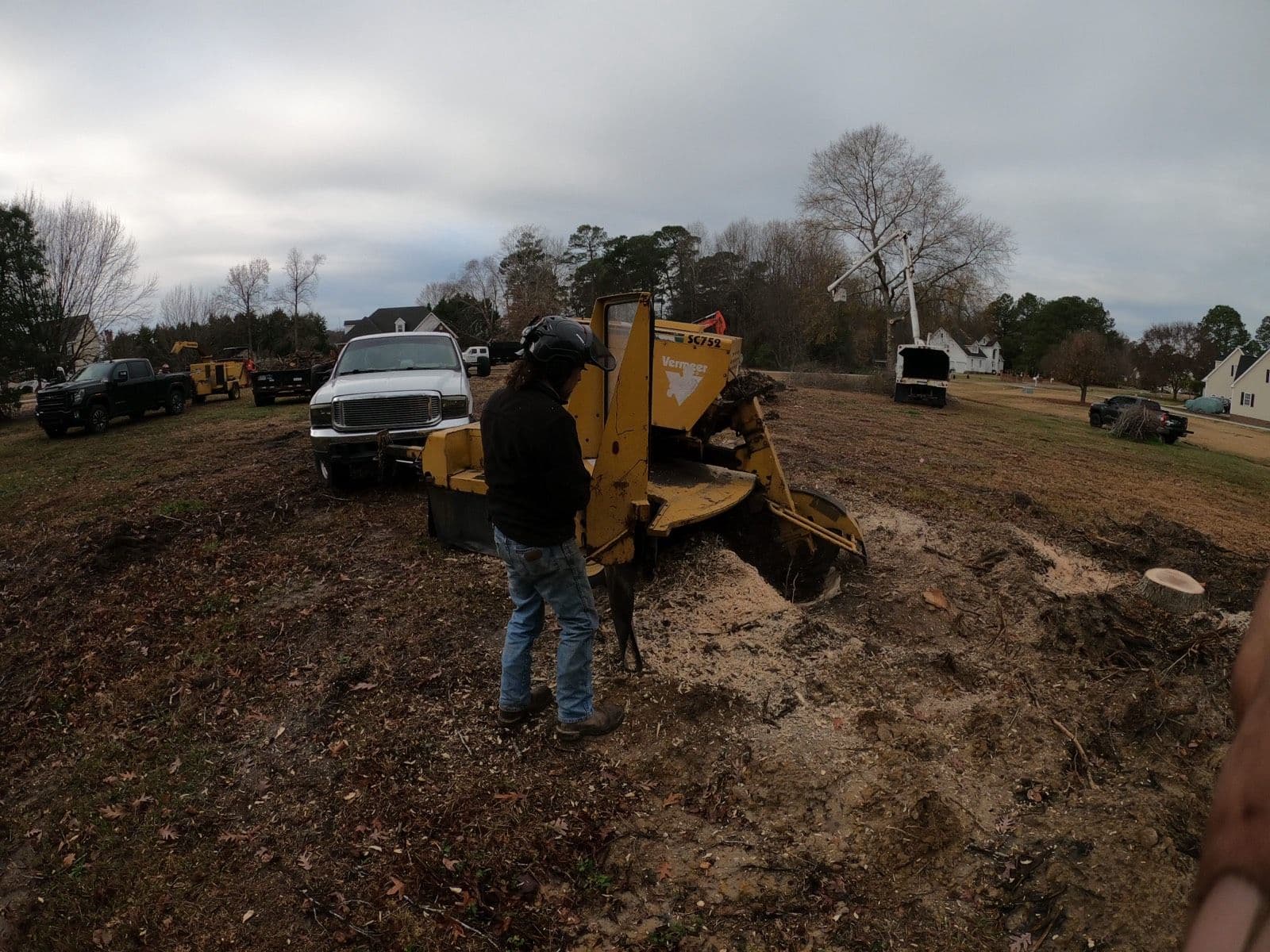 Tree Works crew member running a stump grinder on a cleared residential lot